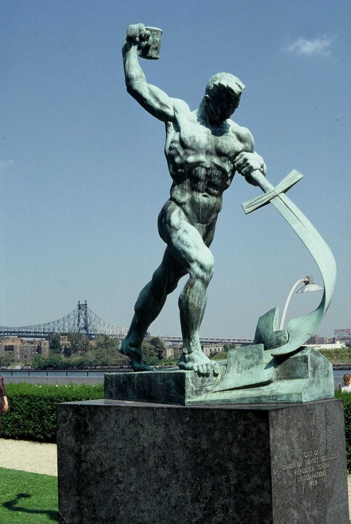 Metal statue of man beating sword to ploughshare